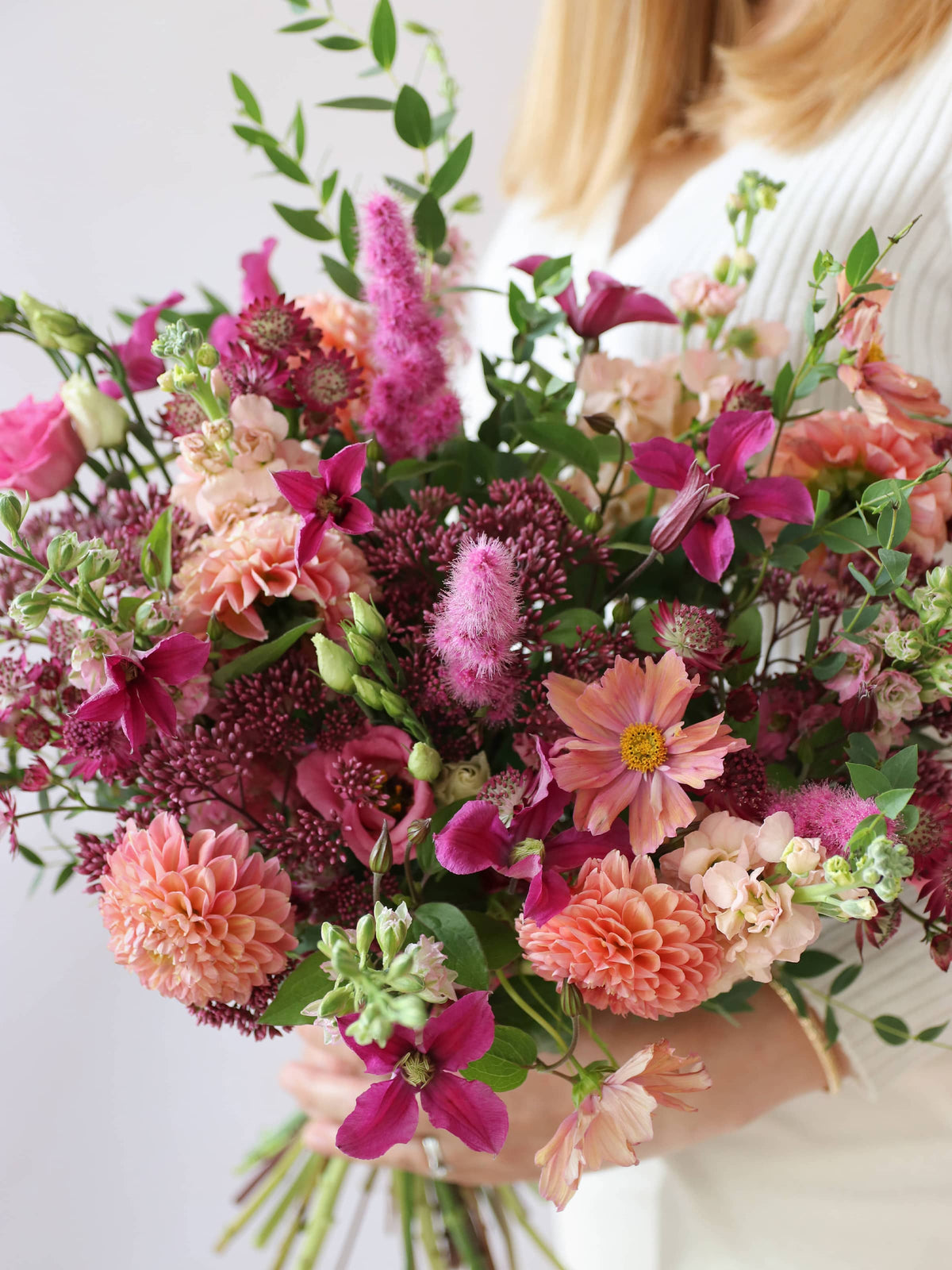 Bouquet of colorful flowers held by a person with a blurred background