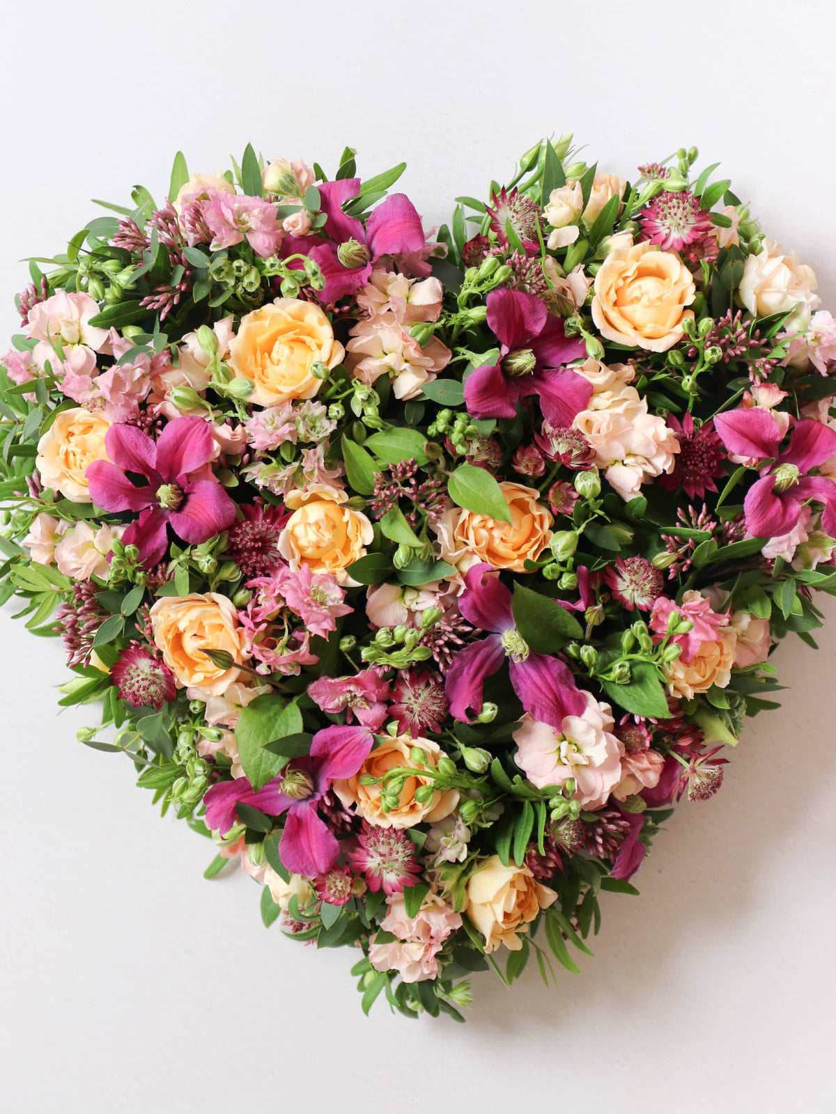 Heart-shaped posy with bright pink and peach flowers on a white background